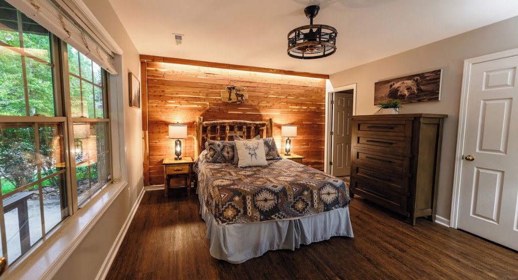 Pigeon Hills master bedroom with king bed wood accent wall antler decor and large windows