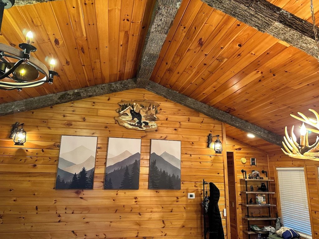 Pigeon Hills vaulted wood ceiling with log beams antler chandelier and mountain artwork